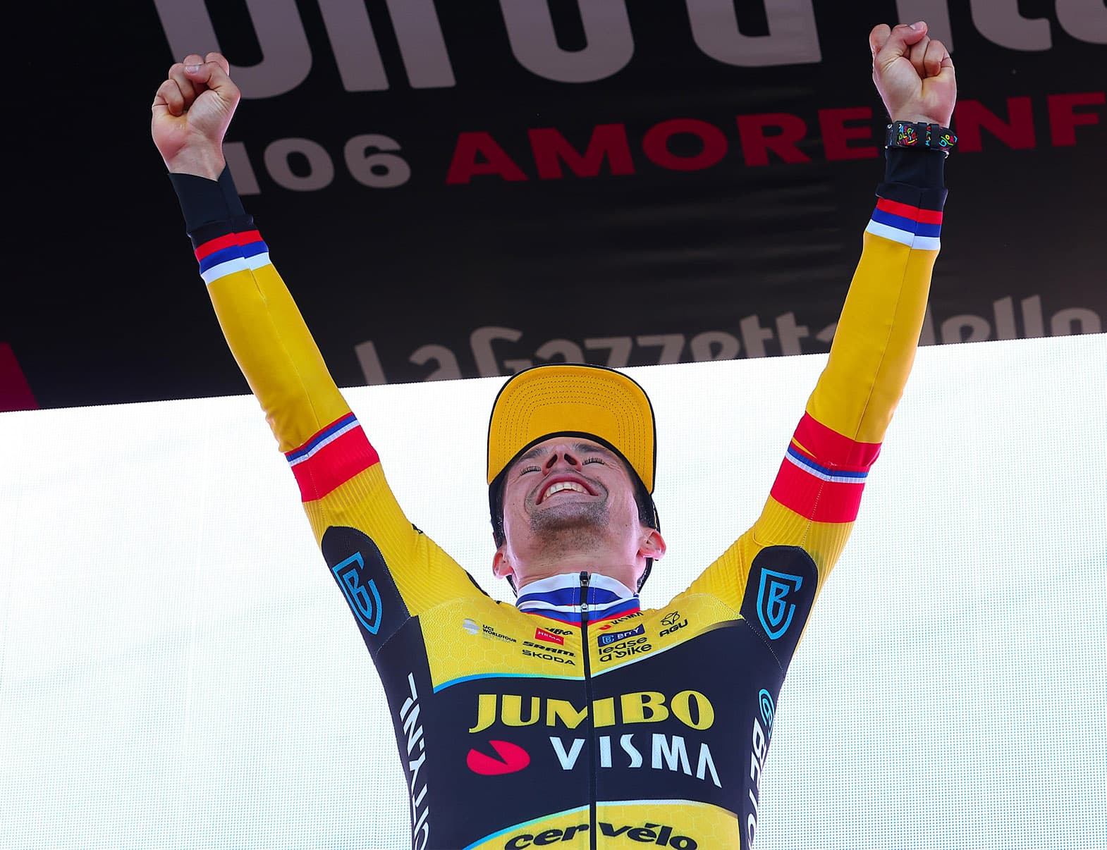 Primož Roglič with is arms in the air cheering in celebration of his time trial victory.