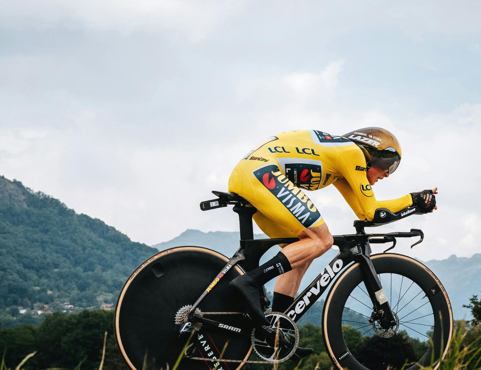Jonas Vingegaard wearing Yellow and riding his Cervélo P5 time trial bike with mountains in the background.